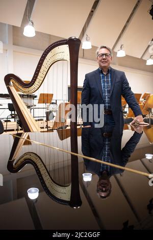 Brême, Allemagne. 09th juin 2022. Christian Kötter-Lixfeld, directeur artistique de l'Orchestre philharmonique de Brême, se trouve à côté d'une harpe dans la nouvelle salle de concert du Tabakquartile. L'Orchestre philharmonique de Brême vient de se déplacer dans sa nouvelle maison ici. Ici, ils ont leur propre hall avec plus de 400 mètres carrés d'espace et 373 sièges à leur disposition comme salle de répétition et d'événement. (À la musique dpa du quartier du tabac - Orchestre philharmonique de Brême en mouvement) crédit: Sina Schuldt/dpa/Alay Live News Banque D'Images