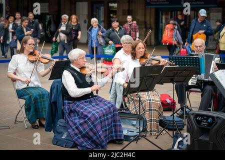 Les membres de l'Orchestre du violon écossais jouent dans une représentation pop-up à la gare Waverley d'Édimbourg, dans un court concert de musique traditionnelle de leur répertoire pour divertir les passants sur le hall avant leur prochain concert à Usher Hall samedi. Date de la photo: Jeudi 9 juin 2022. Banque D'Images