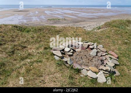 Restes d'un feu de camp sur les dunes de sable côtières sur le front de mer, susceptible de causer des dommages à la végétation et d'aggraver l'érosion côtière, Kenfig NNR, pays de Galles. Banque D'Images