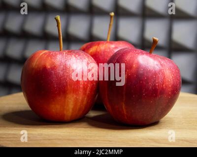 Trois pommes rouges sur une surface en bois. Pommes de la variété Gala. Banque D'Images