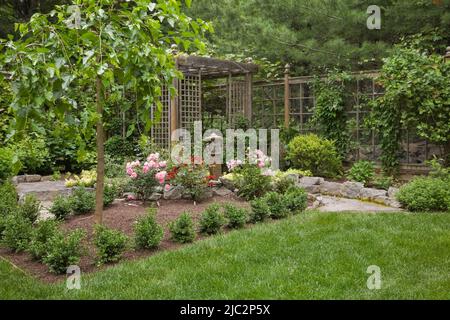 Chemins en pierre menant à la pergola dans le jardin résidentiel paysagé de cour en été. Banque D'Images