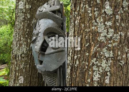 Gros plan de la sculpture entre deux arbres en bordure dans le jardin résidentiel paysagé d'arrière-cour en été. Banque D'Images