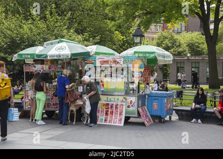 Les gens prennent un en-cas à un vendeur de nourriture à City Hall Park le long de Park Row à Manhattan, New York. Banque D'Images