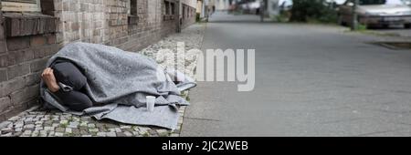Sans-abri couvert d'une couverture dormir sur rue en ville Banque D'Images