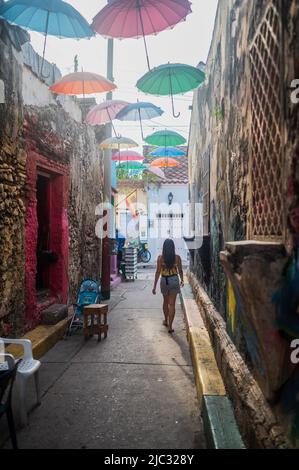 Jeune femme marchant dans la rue populaire couverte de parapluie dans le quartier frais de Getsemani, Cartagena de Indias, Colombie Banque D'Images