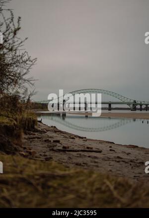 Naufrage sur une plage de sable, Wigg Island, avec le pont Runcorn / Silver Jubilee Bridge en arrière-plan - Runcorn, Royaume-Uni. Banque D'Images