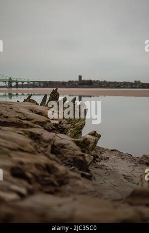 Naufrage sur une plage de sable, Wigg Island, avec le pont Runcorn / Silver Jubilee Bridge en arrière-plan - Runcorn, Royaume-Uni. Banque D'Images