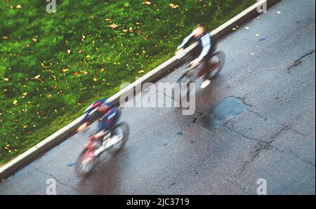 les cyclistes font du vélo de sport le long de la rue automnale Banque D'Images