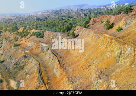 Reboisement de l'ancienne mine à ciel ouvert. Pins poussant sur le mur à gradins de la mine de sulfures abandonnée à Limni, Chypre Banque D'Images