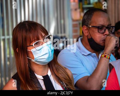 Medellin, Antioquia, Colombie - 19 février 2022 : une femme colombienne aux cheveux longs rouges porte des lunettes blanches et un masque cyan sur la rue près d'autres PE Banque D'Images