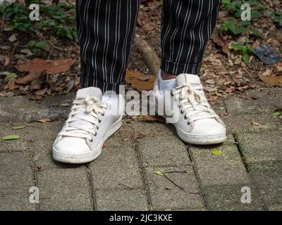 Femme portant un pantalon à rayures noires, des chaussettes blanches et des chaussures blanc cassé Banque D'Images