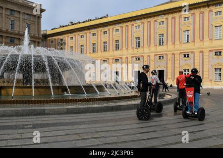 Touristes à cheval Segway véhicules électriques à côté de la fontaine sur la place Piazza de Ferrari avec le Palais des Doges en arrière-plan, Gênes, Ligurie Banque D'Images