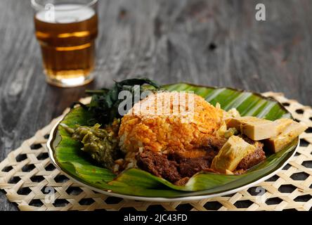 Nasi Padang servi avec Rendang, Curry de jeune Jackfruit, feuilles de manioc, et Sambal Hijau ou Lado Mudo. Sur une table en bois Banque D'Images