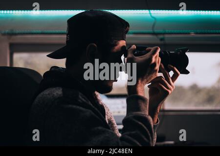 Profil d'un jeune homme tenant un appareil photo Banque D'Images