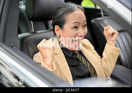 Belle femme d'affaires asiatique ou directrice générale senior qui reçoit les meilleures nouvelles en voiture. Excitée, criant avec une bonne expressio Banque D'Images
