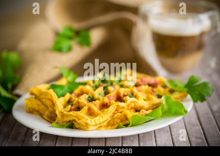 Omelette aux œufs farcie avec des légumes verts et des saucisses frits sous forme de gaufres, sur une table en bois Banque D'Images