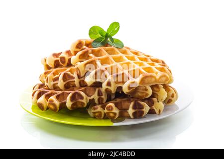 Wafers de fromage cottage doux avec une branche de menthe dans une assiette, isolée sur un fond blanc. Banque D'Images