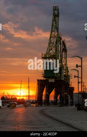 Des grues historiques sur les boulevards au bord de la rivière à Szczecin pendant un lever de soleil spectaculaire Banque D'Images