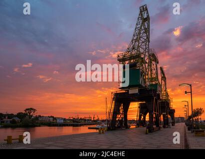 Des grues historiques sur les boulevards au bord de la rivière à Szczecin pendant un lever de soleil spectaculaire Banque D'Images