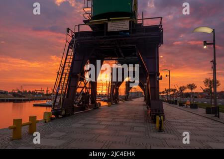 Des grues historiques sur les boulevards au bord de la rivière à Szczecin pendant un lever de soleil spectaculaire Banque D'Images