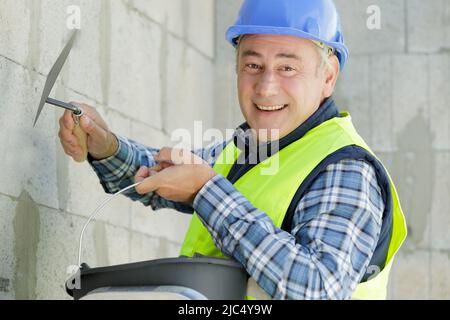 Travailleur de la construction avec un mur plâtrage truelle longue Banque D'Images