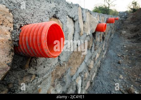 Une rangée de ponceaux orange ou de tuyaux de sortie d'eau à travers un mur de retenue en pierre pour le drainage des tempêtes dans les collines d'Uttarakhand Inde. Banque D'Images