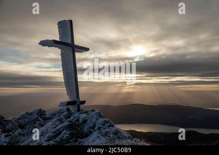 Le ciel raye derrière un monument commémoratif de la Croix de fer, près du sommet de Ben Ledi, à Stirling, en Écosse Banque D'Images