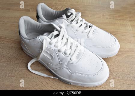 Nouvelles baskets blanches élégantes, confortables et pratiques, sur parquet Banque D'Images