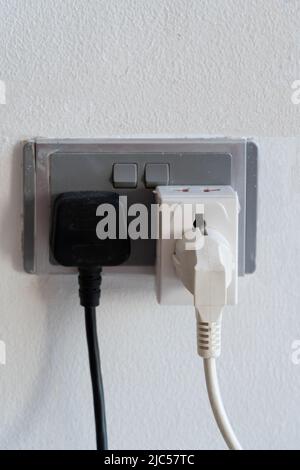 Gros plan des deux prises électriques des appareils électriques branchés dans les prises électriques du mur. Banque D'Images