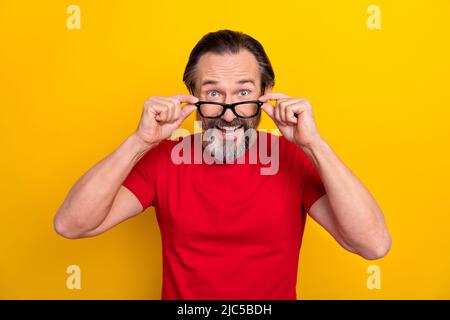 Photo de l'impressionné funky gars pensioner habillé rouge t-shirt bras lunettes bouche ouverte isolé couleur jaune arrière-plan Banque D'Images