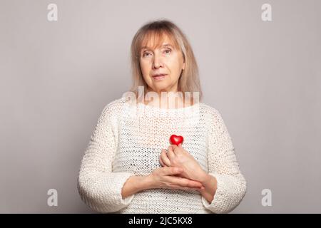 Portrait d'une femme âgée attrayante tenant le cœur rouge dans ses mains Banque D'Images
