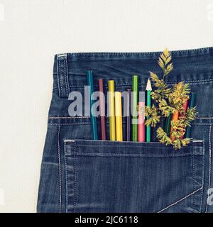 Un groupe de crayons de couleur et une pointe verte dans une poche de Jean Banque D'Images