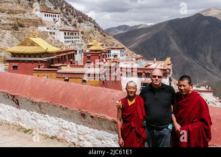 Un touriste avec deux jeunes moines au Monastère de Ganden au sommet de la montagne de Wangbur le 1st et le monastère primaire de l'école Gelug du bouddhisme tibétain. Banque D'Images