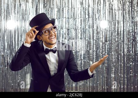 Joyeux sourire homme en costume, chapeau et lunettes présente quelque chose sur fond vierge Banque D'Images