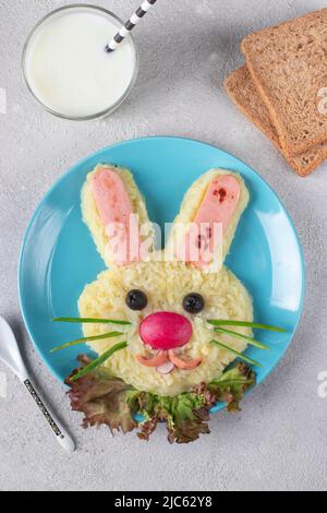 Lapin drôle de purée de pommes de terre et de saucisses, yaourt naturel en verre et pain pour le petit déjeuner repas des enfants. Menu enfant créatif, format vertical Banque D'Images