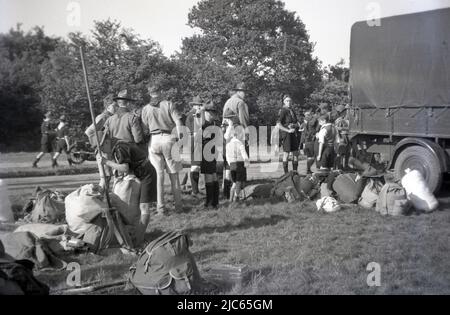 1937, historique, se remballer après un camp de scouts à Ranmore Common, Dorking, Surrey, Angleterre, Royaume-Uni. Des scouts en uniforme et des scouts de garçon debout à côté des sacs à dos de toile de l'époque, emballés et prêts à aller dans le camion d'attente. Banque D'Images