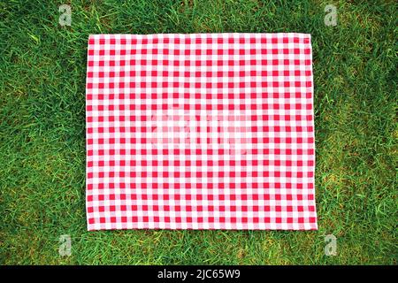 Tissu carré pique-nique rouge sur herbe verte vue du dessus, exposition de nourriture. Serviette à carreaux. Serviette de table à motif Vichy. Banque D'Images