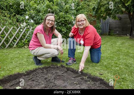 Schenefeld, Allemagne. 10th juin 2022. Ilka Rau (l), coordinatrice du projet 'Schenefeld Digs Out', et Maike Beer- von Aspern, propriétaire de la parcelle de jardin, s'assoient devant un trou d'excavation fraîchement creusé. Dans les lieux privés et publics, les archéologues ont mis 20 petites surfaces d'un mètre carré chacune, afin de laisser là sous la direction des habitants et des habitants de Schenefeld chercher les excavations accomplir. Selon les informations, c'est un projet unique en Allemagne. Credit: Georg Wendt/dpa/Alay Live News Banque D'Images