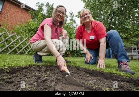 Schenefeld, Allemagne. 10th juin 2022. Ilka Rau (l), coordinatrice du projet 'Schenefeld gräbt aus', et Maike Beer- von Aspern, propriétaire de la parcelle de jardin, s'assoient devant un trou d'excavation fraîchement creusé. Dans les lieux privés et publics, les archéologues ont mis 20 petites surfaces d'un mètre carré chacune, afin de laisser là sous la direction des habitants et des habitants de Schenefeld chercher les excavations accomplir. Selon les informations, c'est un projet unique en Allemagne. Credit: Georg Wendt/dpa/Alay Live News Banque D'Images