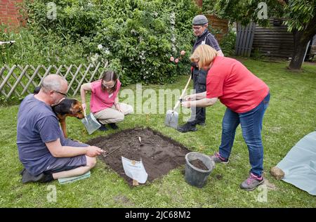 Schenefeld, Allemagne. 10th juin 2022. Stefan Scholle (l-r), employé de l'état, chien Maja, Ilka Rau, coordinateur du projet 'Schenefeld gräbt aus', Volker Schade, retraité, et Maike Beer- von Aspern, propriétaire du terrain de jardin, se tiennent autour d'un trou d'excavation fraîchement creusé. Sur les lieux privés et publics, les archéologues ont mis 20 petites zones d'un mètre carré chacune, afin de laisser là sous la direction les habitants et l'habitant à l'intérieur de Schenefeld les fouilles de recherche accomplir. Selon les informations, c'est un projet unique en Allemagne. Credit: Georg Wendt/dpa/Alay Live News Banque D'Images