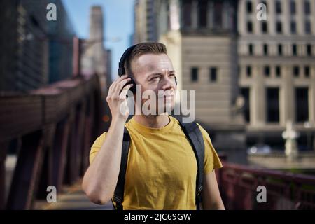 Portrait de l'homme tout en écoutant de la musique avec des écouteurs sans fil pendant la promenade en ville. Banque D'Images