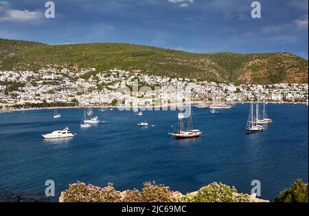 Vue sur la plage de Bodrum depuis le château. Bateaux à voile, yachts à la mer Égée avec maisons blanches traditionnelles sur les collines de la ville de Bodrum en Turquie Banque D'Images