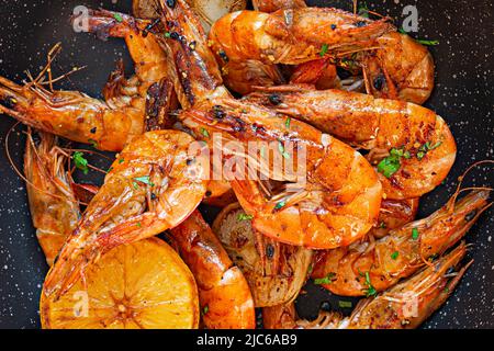 Grandes crevettes grillées (tigre) cuites dans une poêle avec épices, herbes et citron sur fond sombre. Banque D'Images