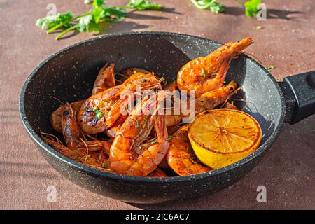 Grandes crevettes grillées (tigre) cuites dans une poêle avec épices, herbes et citron sur fond sombre. Banque D'Images