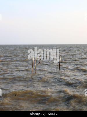 Abandonné par la suite les poteaux en bambou de Rotten d'un ancien quai avec l'aspect abstrait incliné dans la mer. Banque D'Images