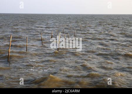 Abandonné par la suite les poteaux en bambou de Rotten d'un ancien quai avec l'aspect abstrait incliné dans la mer. Banque D'Images