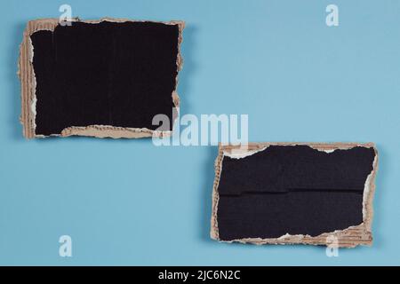 Deux morceaux de carton ondulé noir dont les bords sont déchirés sur fond bleu clair. Vue de dessus, espace de copie Banque D'Images