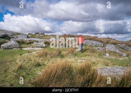 Un marcheur portant une veste rouge vif marchant sur Stowes Hill sur Bodmin Moor en Cornouailles. Banque D'Images