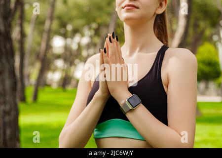 Vue rognée de la jeune femme brune portant des vêtements de sport sur le parc de la ville, à l'extérieur garder les mains dans la prière se sentir superstititititititieux religieux. Dieu. La foi, soyez Banque D'Images