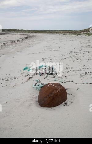 Flotsam et débris marins sur la ligne haute d'une plage de sable blanc à North Uist, Hébrides extérieures, comprenant une corde, un filet et un poids en fer Banque D'Images